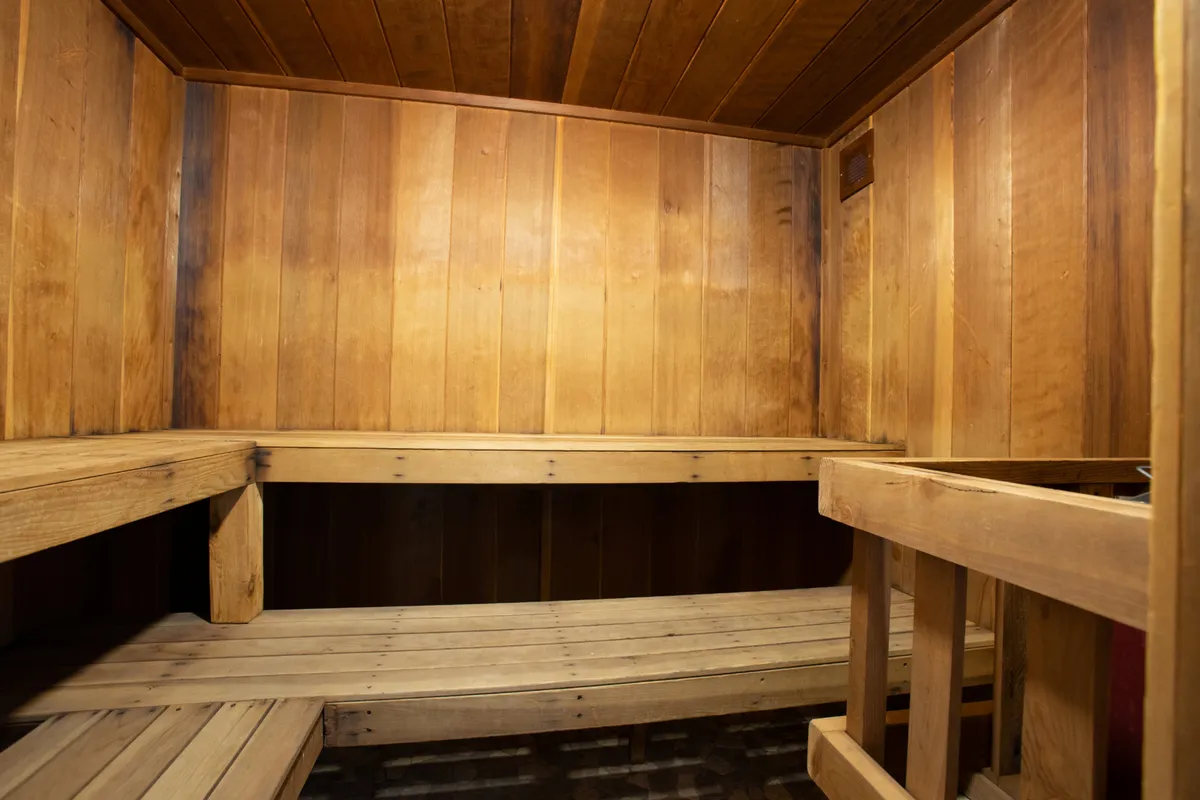 A calming sauna space with wooden benches and walls, designed for wellness routines and relaxation. The inviting warmth and simplicity make it ideal for unwinding muscles after skiing.