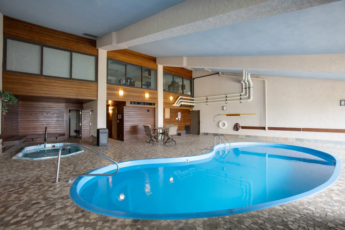 This indoor pool and hot tub area features wood-paneled walls, lounge chairs, and soft lighting, creating a calming and rejuvenating ambiance. The pool and hot tub are ideal for relaxation and socializing, regardless of the season.